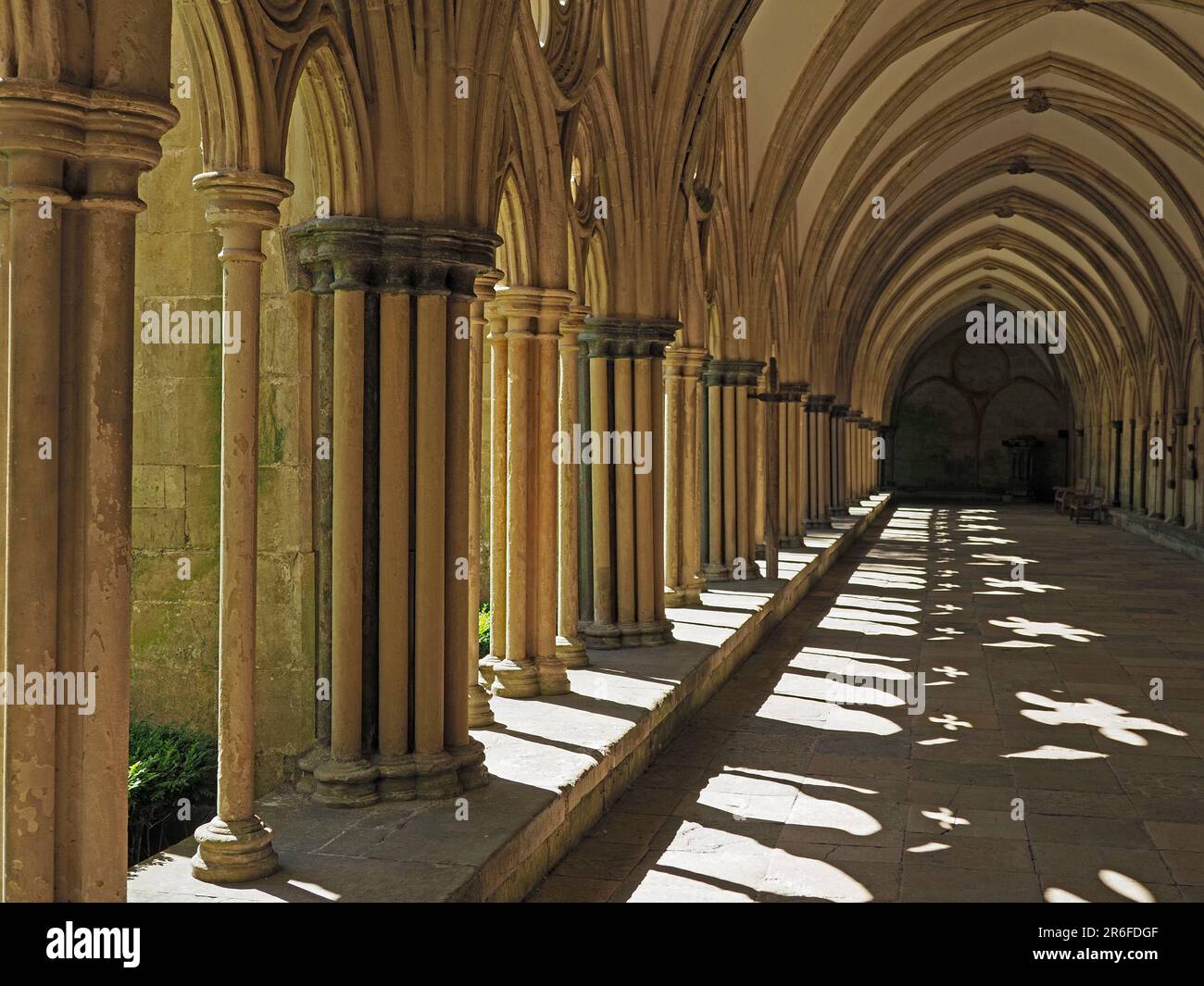 Antikes Lichtmuster und Schatten, die von Sonnenschein durch Bögen in historischen Klostern der Salisbury Cathedral, Wiltshire, England, geworfen werden Stockfoto