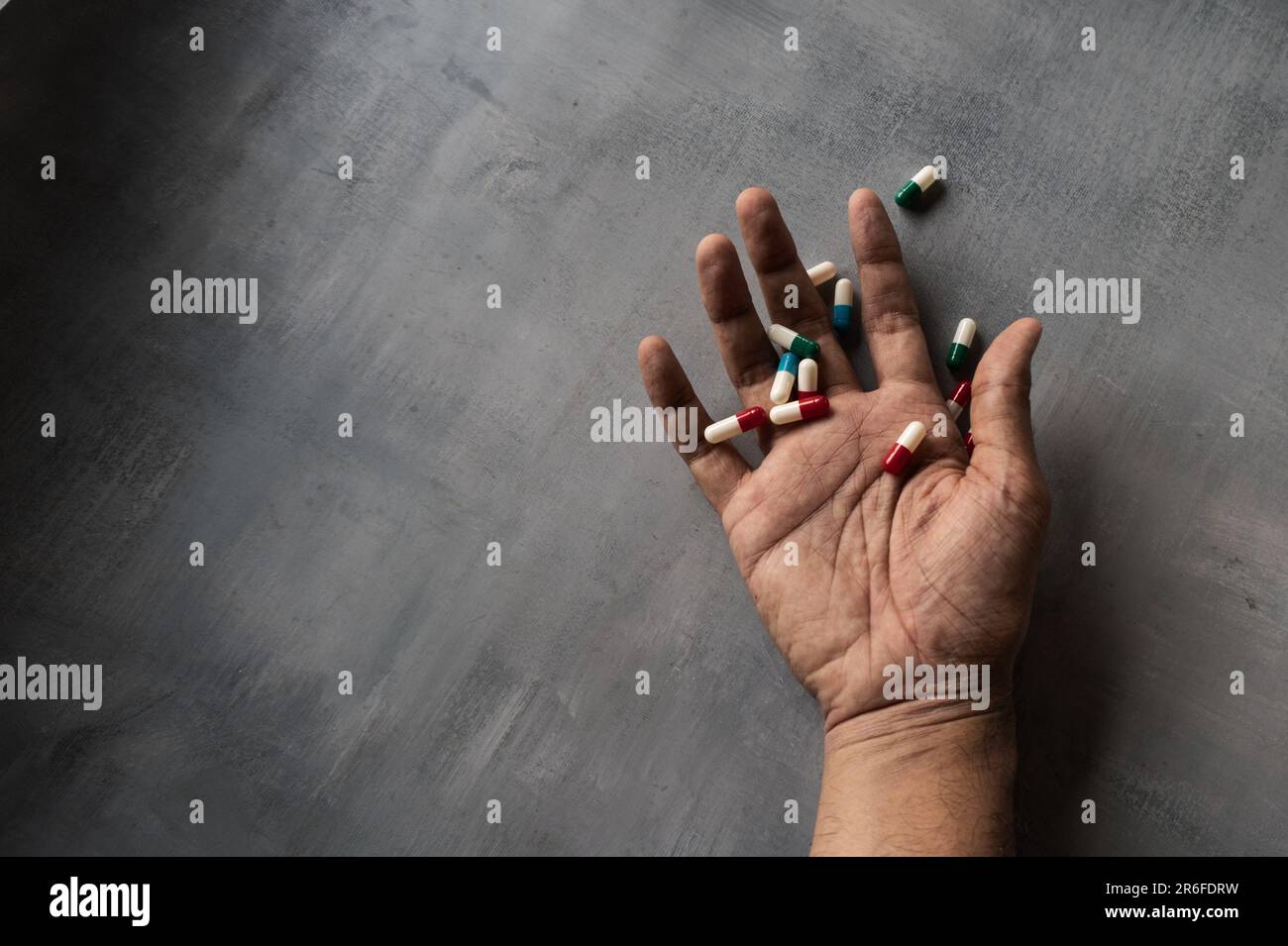 Nahaufnahme von Hand und Pillen auf Betonboden mit Kopierraum. Uberdosis, Drogenabhängiger und Suizidkonzept Stockfoto