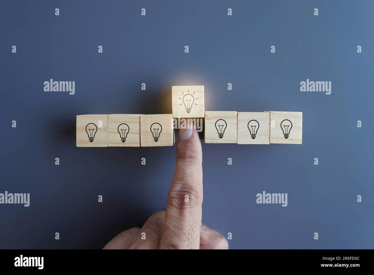 Wählen Sie von Hand einen Holzblock mit einer Glühbirne aus. Brainstorming, gute Ideen, Lösungskonzept Stockfoto