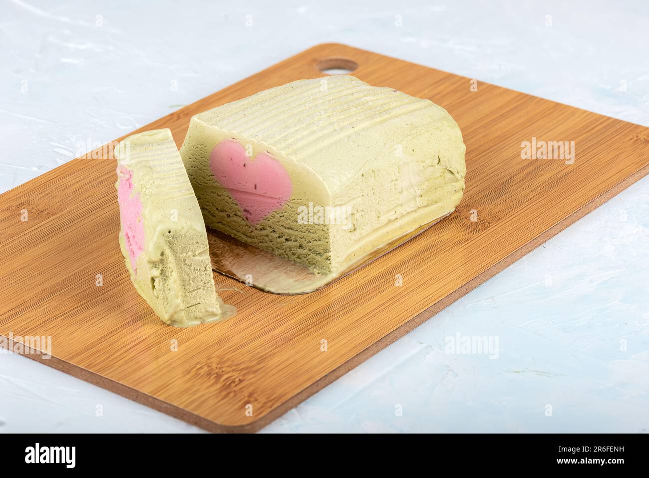 Pistazieneis mit einer herzförmigen Himbeerschicht auf einem Schneidebrett. Speicherplatz kopieren. Stockfoto