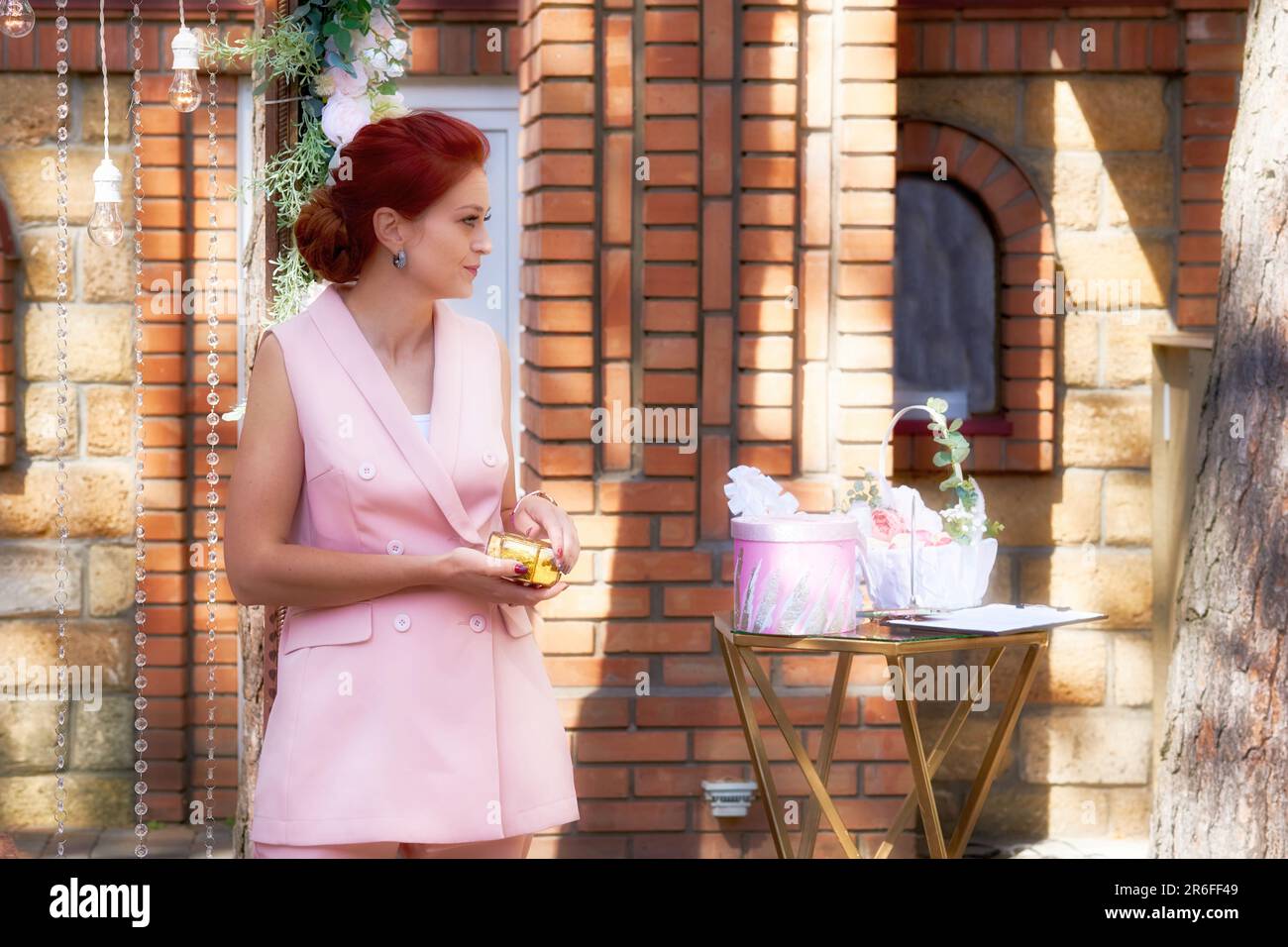 Süßer Geburtstagsgeschenk, Hochzeitsveranstalter und Veranstaltungsveranstalter in pinkfarbenem Hosenanzug, der auf Gäste wartet Stockfoto