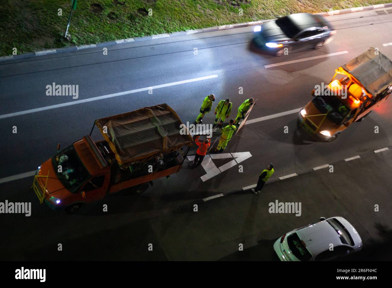 Die Arbeiter machen nachts neue Straßenmarkierungen. Lackierschild für Fahrspur des öffentlichen Nahverkehrs. Ukraine, Charkiv - 1. Juni 2023 Stockfoto