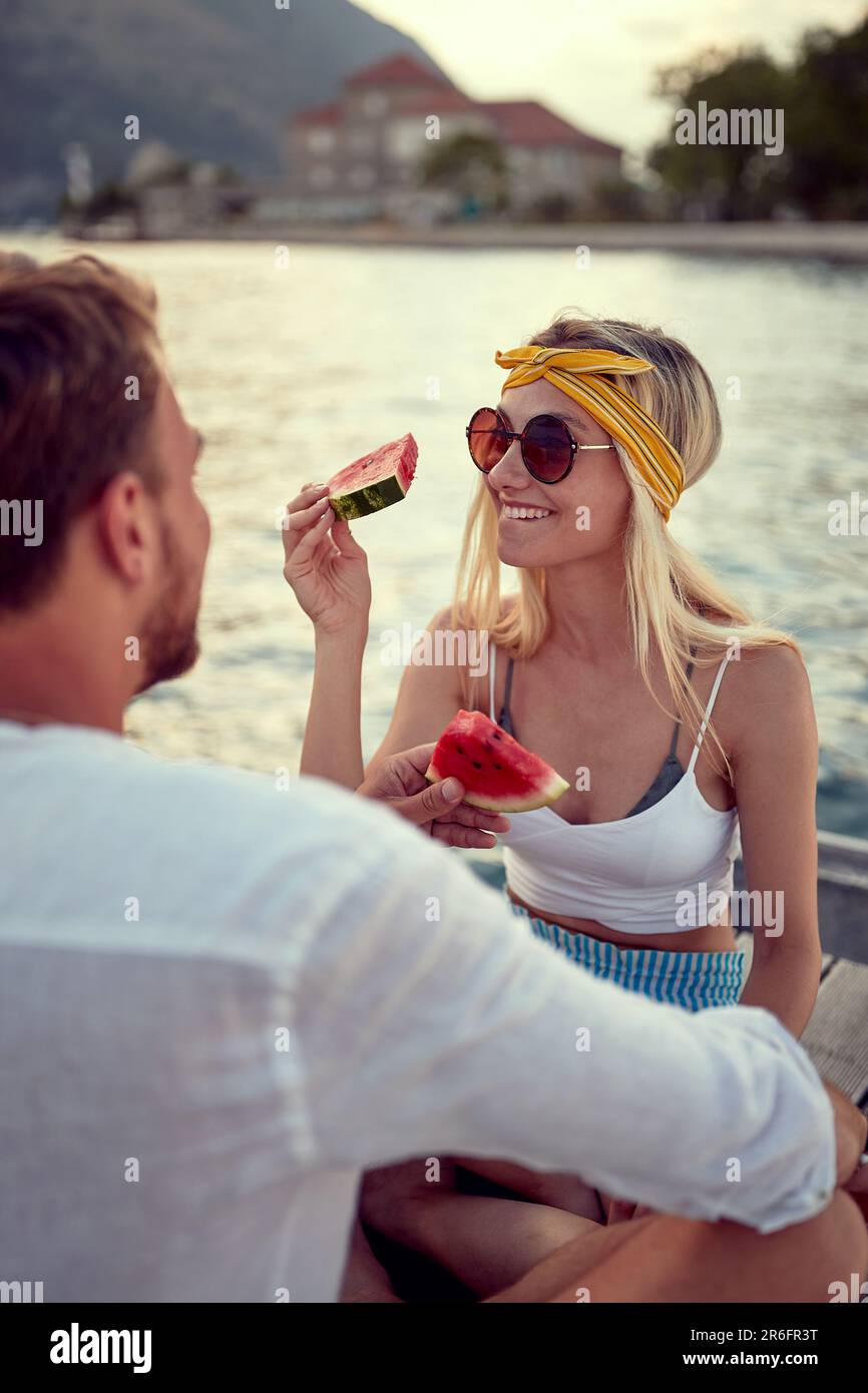 Ein Paar auf einem Date, das alberne Zeit miteinander genießt. Datum auf dem Holzdock auf dem Seeweg. Liebe, Spaß, Zusammensein Konzept. Stockfoto