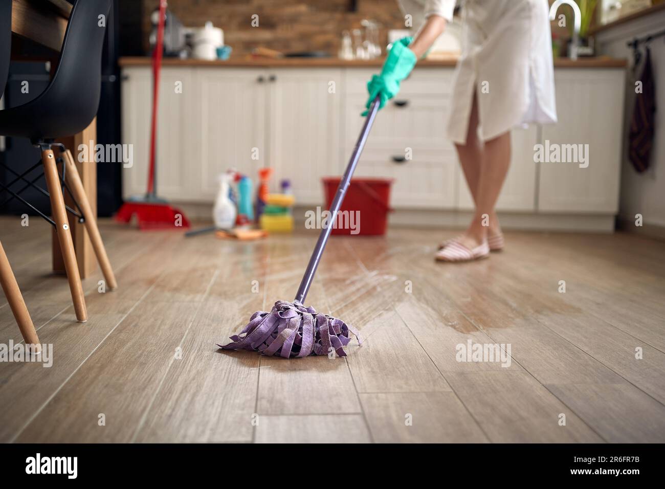 Gesichtslose Aufnahme von Hausfrauenfußboden in der Küche, mit chemischen Flaschen im Hintergrund. Haus, Reinigung, Lifestyle-Konzept. Stockfoto