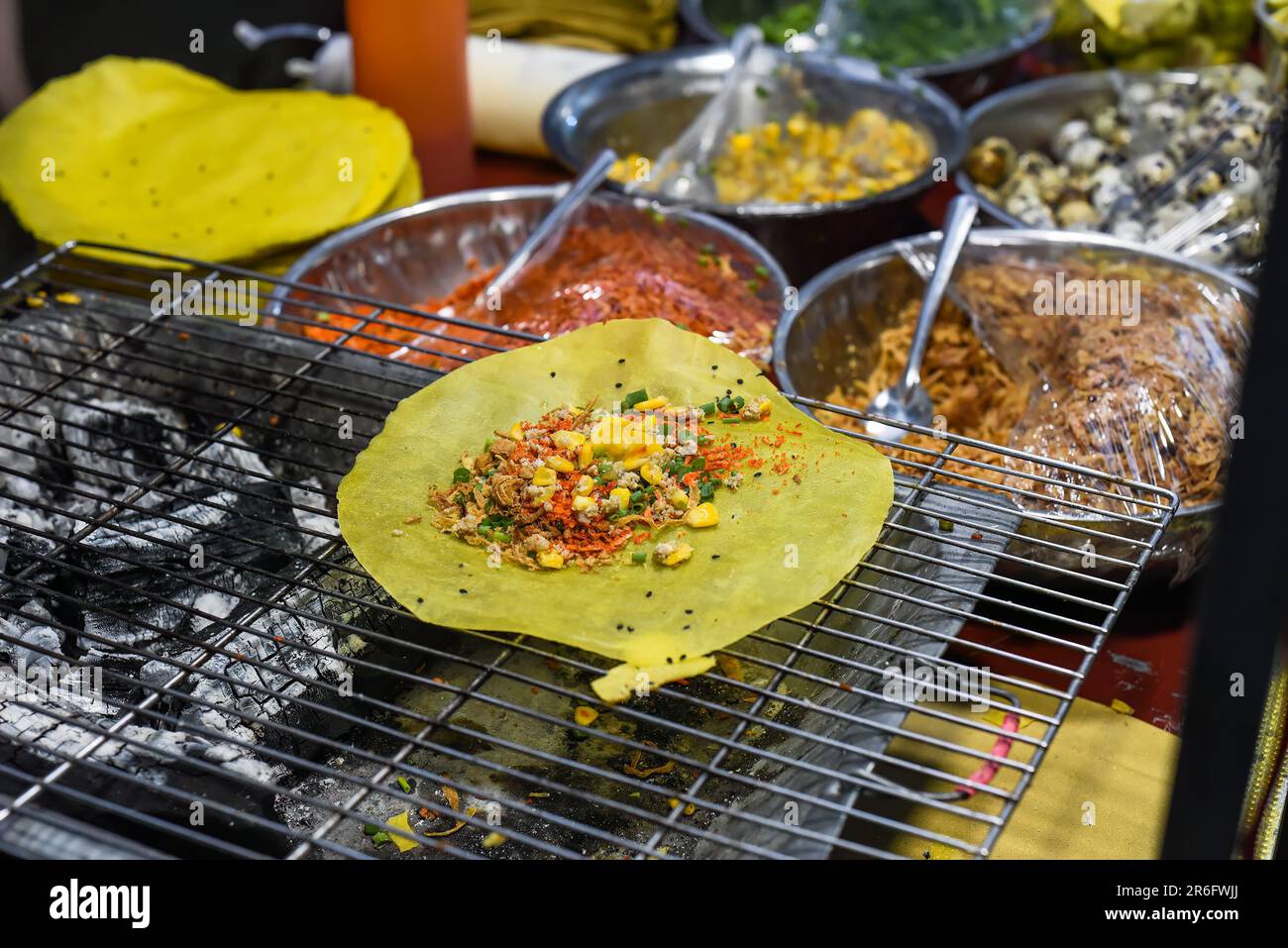 Gegrillter vietnamesischer Pfannkuchen mit Eiern, Würstchen und Saucen auf dem vietnamesischen Nachtmarkt beim Food Festival Stockfoto