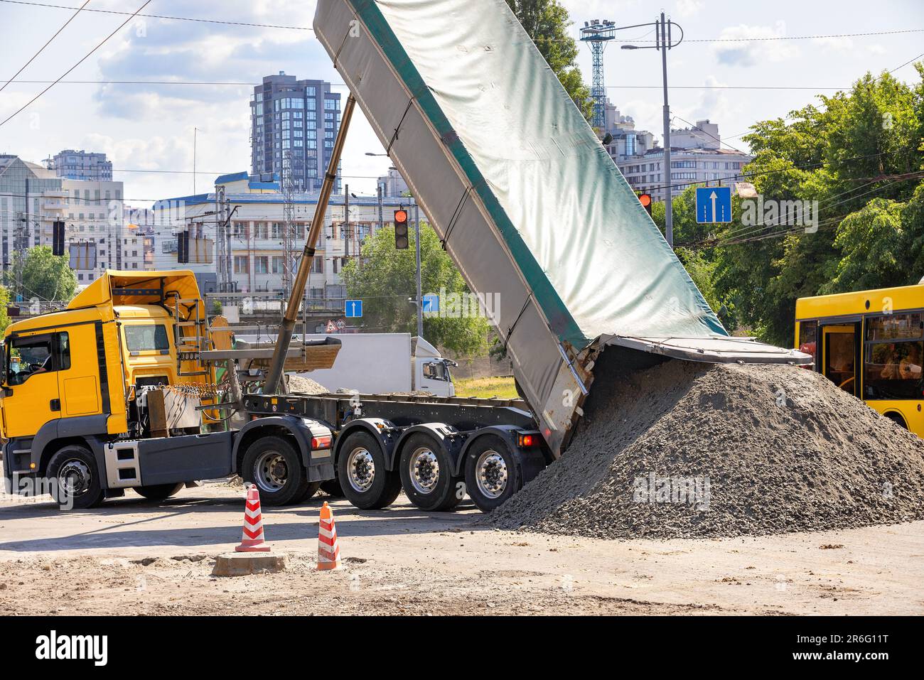 Autotonar für den Transport von schwerem Massengut großer Kipplaster entlädt Zementsandgemische auf Straßenbaustellen. Stockfoto