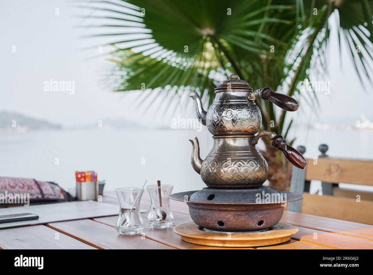 Traditionelle türkische Teekanne mit doppelten Teekannen auf einem Stand mit Kohlen in einem Café, selektiver Fokus. Kupferteekanne und Gläser auf dem Tisch, Tee Stockfoto