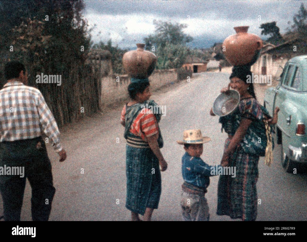 1950er – Guatemala, Frauen tragen Wassergläser auf den Köpfen, während sie die Straße hinuntergehen Stockfoto