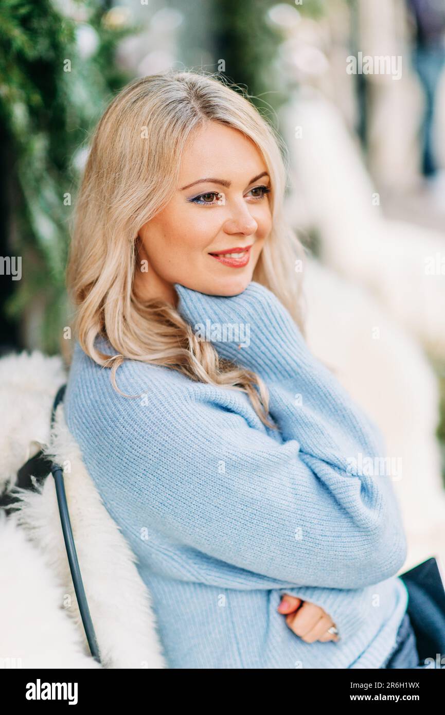 Winterporträt einer schönen Frau mit blondem Haar, die einen blauen Pullover trägt Stockfoto
