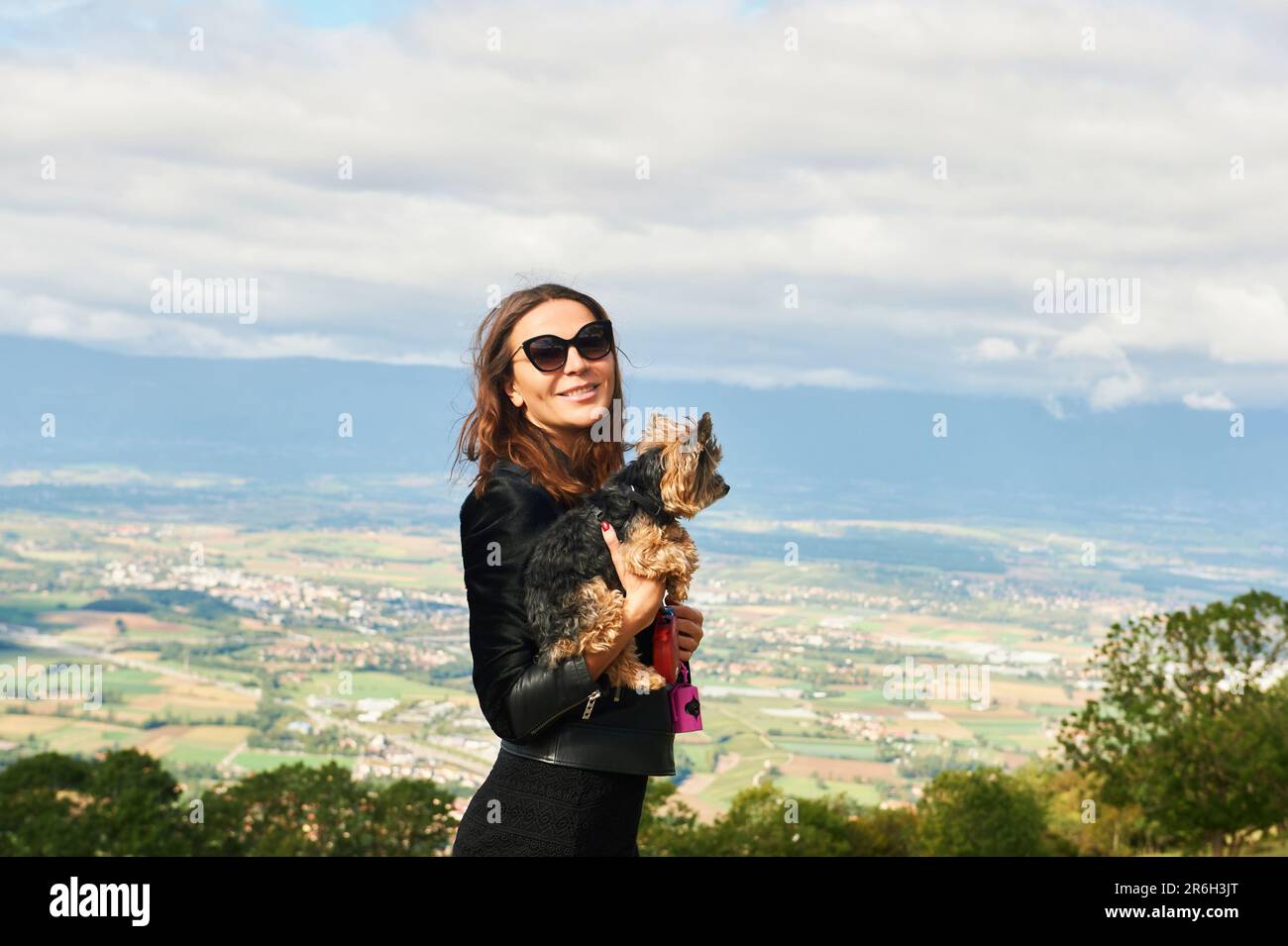 Außenporträt von einer hübschen Frau, die einen Yorkshire-Terrier-Hund hält Stockfoto