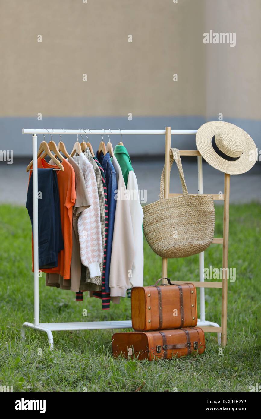 Kleiderständer mit verschiedenen Kleidungsstücken im Hof. Garagenverkauf Stockfoto