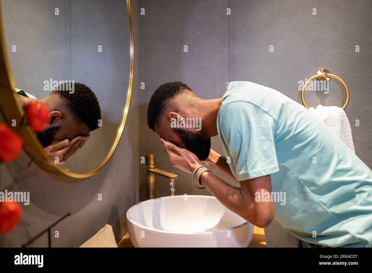 Ein afroamerikanischer Millennials, der morgens die Haut reinigt, sich das Gesicht mit Wasser im Badezimmer wäscht Stockfoto