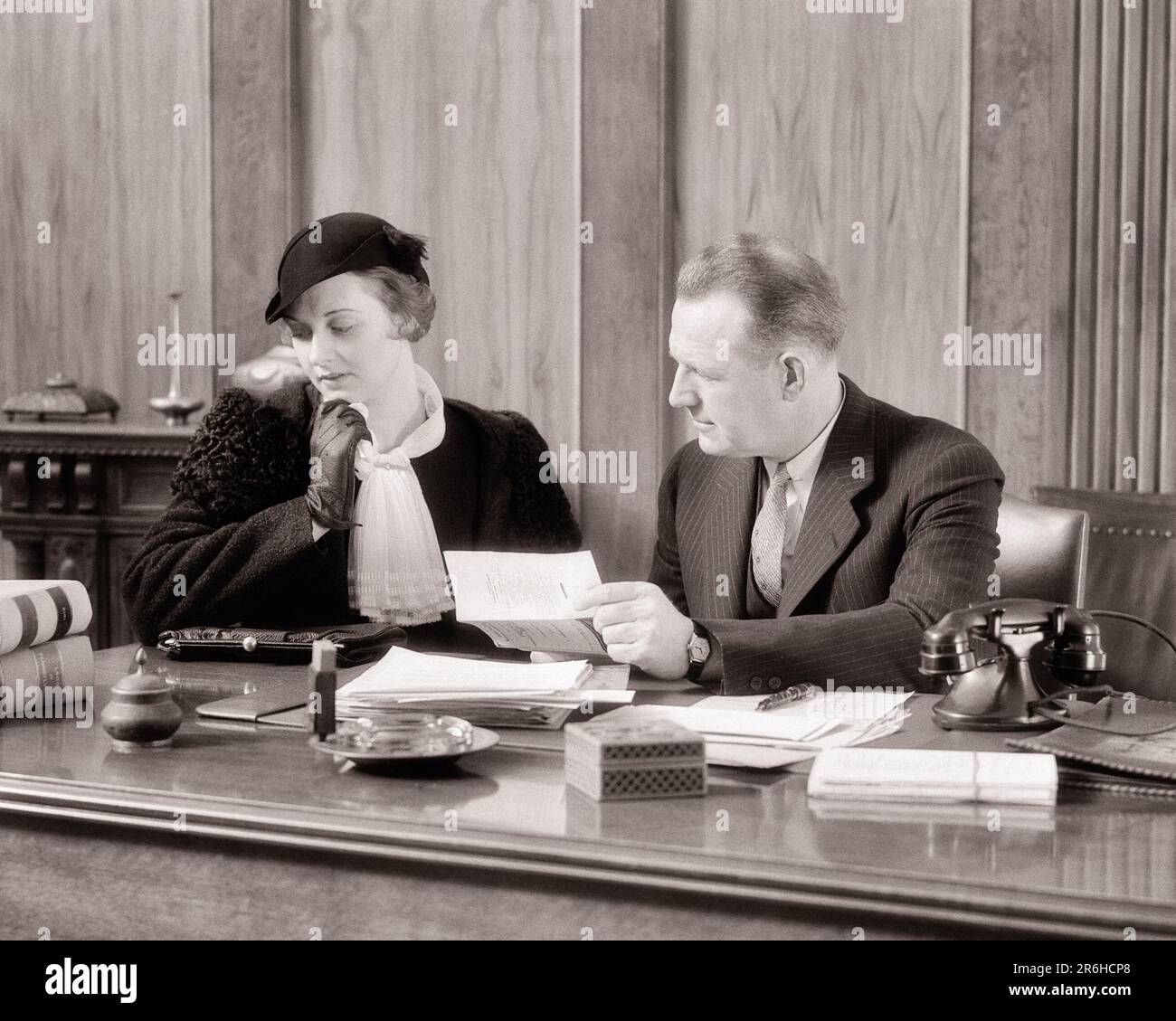 1930S TRAURIGE, MODISCHE FRAU, DIE NEBEN IHREM ANWALT SITZT UND DOKUMENTE PRÜFT, WILL SCHEIDUNGSURTEIL RECHTSBERATUNG - O1336 HAR001 HARS STIL FURCHT KOMMUNIKATION INFORMATIONEN SORGEN MYSTERY MODEWELT LIFESTYLE FRAUEN MOODY SITZT TEXT PLATZ HALBE LÄNGE DAMEN WERDEN MÄNNER BESORGT B&W BESORGT TRAURIGKEITSKLAGE UND KRAWATTE DOKUMENTE ENTDECKUNGSSTILE TOD GERICHTSANWÄLTE URTEILSVERMÖGEN ANWÄLTE STIMMUNG BERUFE TESTAMENT ÜBERPRÜFUNG KONZEPTIONELLE TROST NEBEN STILVOLL DER LETZTE WIRD DIE ANWÄLTE ERBEN ERBÄRMLICHE TESTAMENTE SCHWARZ-WEISS WEISS WEISS, WEISSE ETHNISCHE ZUGEHÖRIGKEIT HAR001 ALTMODISCH Stockfoto 1930S TRAURIGE, MODISCHE FRAU, DIE NEBEN IHREM ANWALT SITZT UND DOKUMENTE PRÜFT, WILL SCHEIDUNGSURTEIL RECHTSBERATUNG - O1336 HAR001 HARS STIL FURCHT KOMMUNIKATION INFORMATIONEN SORGEN MYSTERY MODEWELT LIFESTYLE FRAUEN MOODY SITZT TEXT PLATZ HALBE LÄNGE DAMEN WERDEN MÄNNER BESORGT B&W BESORGT TRAURIGKEITSKLAGE UND KRAWATTE DOKUMENTE ENTDECKUNGSSTILE TOD GERICHTSANWÄLTE URTEILSVERMÖGEN ANWÄLTE STIMMUNG BERUFE TESTAMENT ÜBERPRÜFUNG KONZEPTIONELLE TROST NEBEN STILVOLL DER LETZTE WIRD DIE ANWÄLTE ERBEN ERBÄRMLICHE TESTAMENTE SCHWARZ-WEISS WEISS WEISS, WEISSE ETHNISCHE ZUGEHÖRIGKEIT HAR001 ALTMODISCH Stockfoto