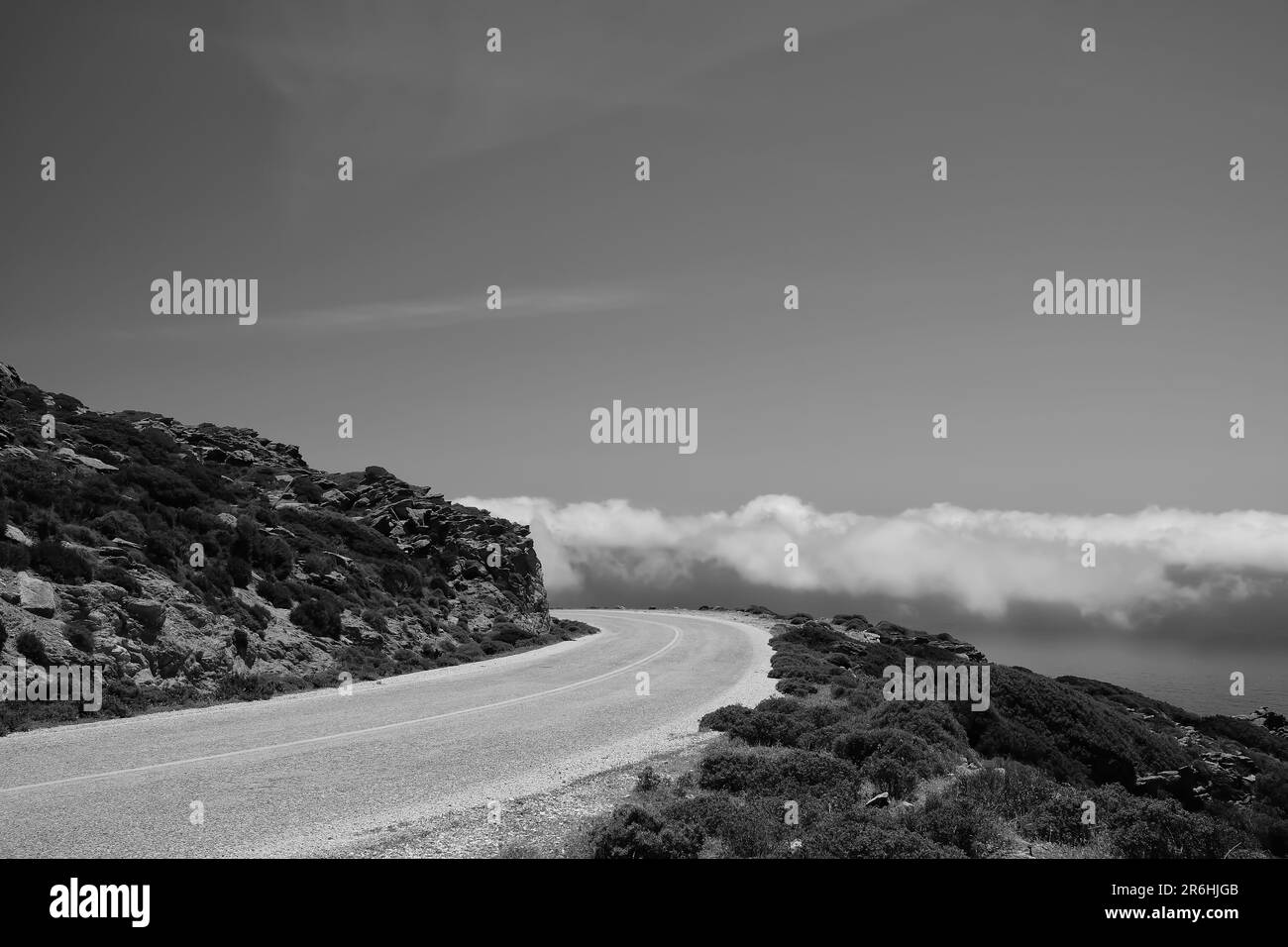 Eine einsame Straße auf einem Hügel und Wolken auf derselben Ebene in iOS kykladen Griechenland in Schwarz und Weiß Stockfoto