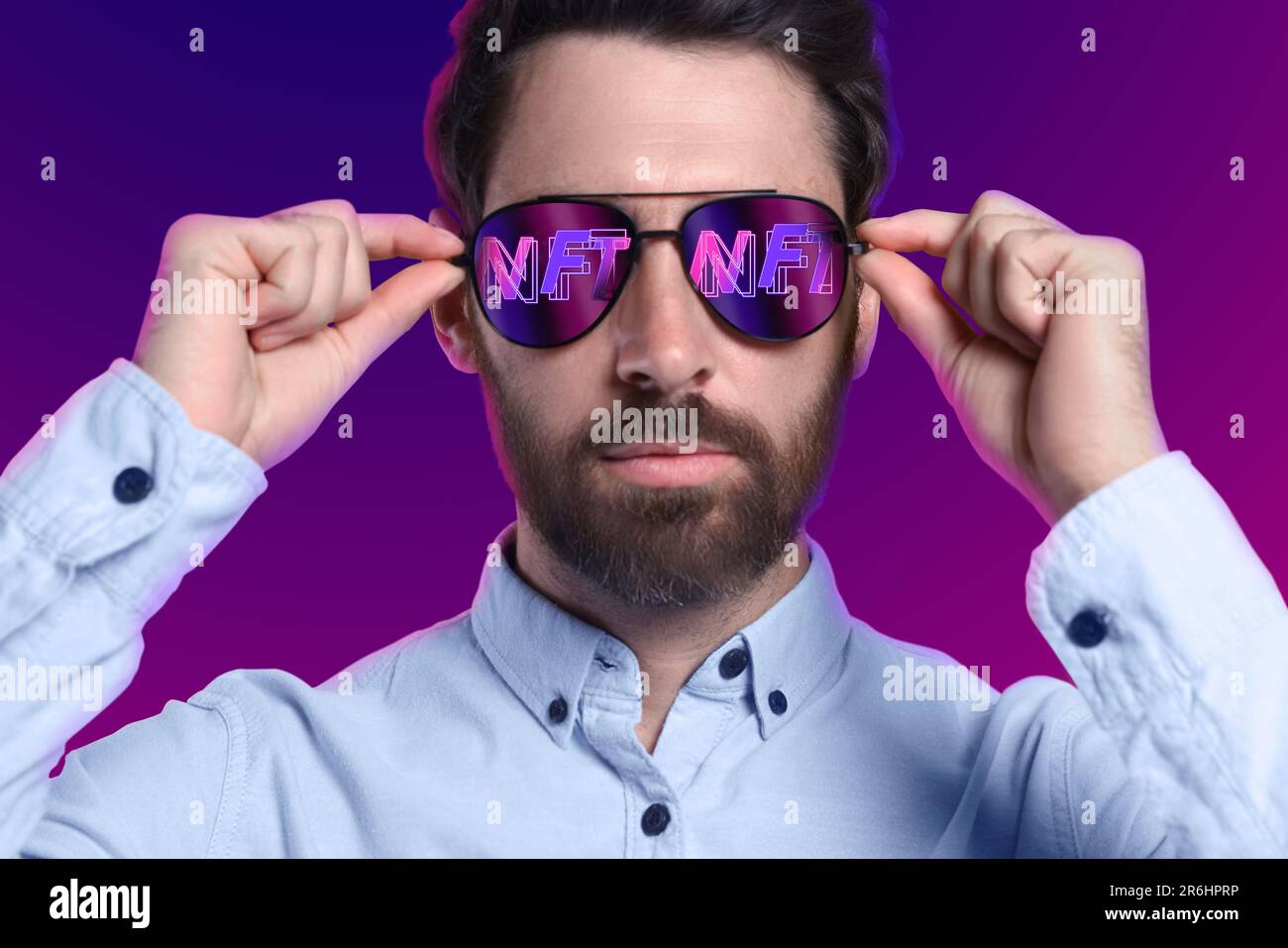 Selbstbewusster Mann mit farbigem Hintergrund. Abkürzung NFT reflektiert in Sonnenbrille Stockfoto