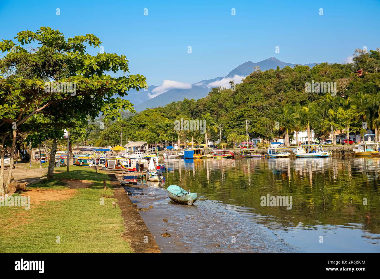 Idyllischer Blick auf den Fluss Perequê-Azu bei lowe Tide mit bunten Tourbooten, Bäumen und Regenwaldbergen an einem sonnigen Tag in der Stadt P, die zum UNESCO-Weltkulturerbe gehört Stockfoto