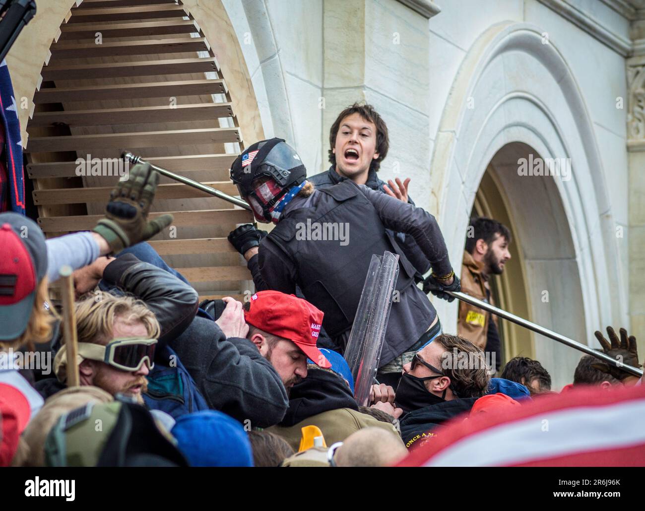 Washington, DC - 6. Januar 2021: David Dempsey, der hier einen Helm und eine Flaggengamasche trägt, greift während des Protests am 6. Januar im Kapitol die Polizei mit einem Fahnenmast an. Die Demonstranten stürmten das Eröffnungsgerüst und brachen trotz des Widerstands von Offizieren und Tränengas in das Gebäude ein. Eine Reihe von Gewalttätern wurde identifiziert und verhaftet. David Dempsey wurde mit Forschungen von Strafverfolgungsbehörden und Freiwilligenteams wie Sedition Hunters identifiziert. Stockfoto