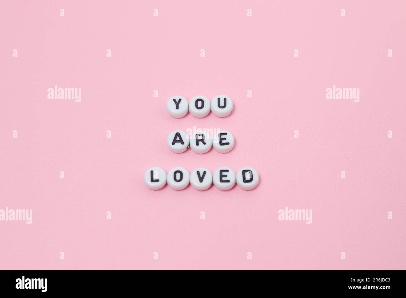 Draufsicht der Zitate „You are love“ aus Perlen auf pinkfarbenem Hintergrund. Motivation und Erfolgskonzept Stockfoto