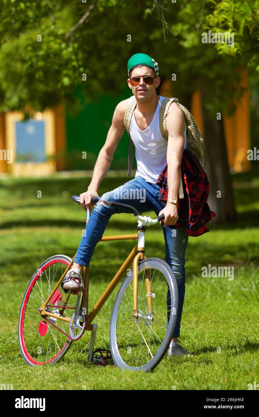 Fahrrad, Park und Porträt eines jungen Mannes für Reisen, Reise und CO2-Bilanz, Straßenbekleidung und coole Mode an der Universität. Person oder Student Stockfoto