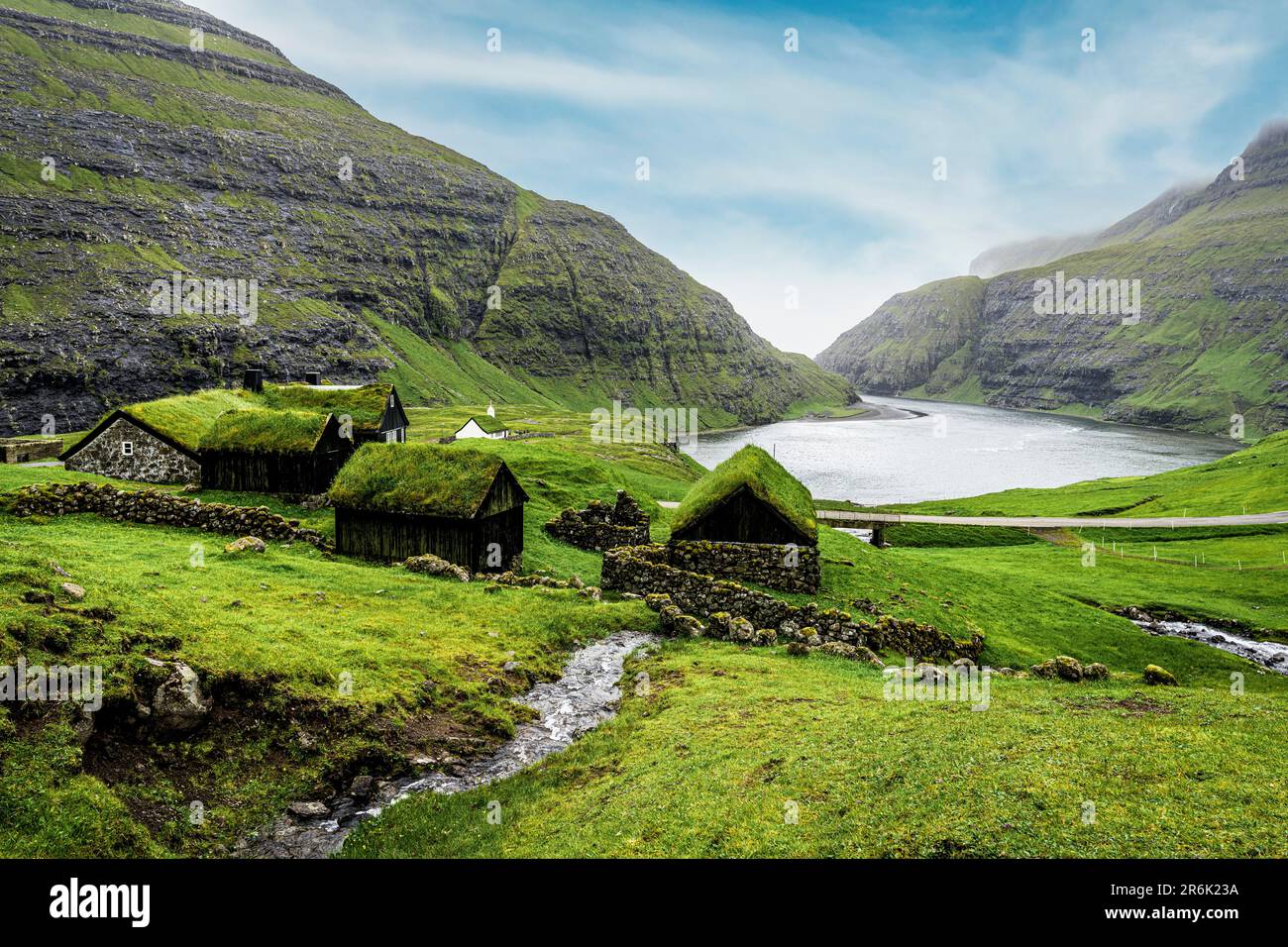 Fluss, der zum Ozean fließt und grüne Wiesen mit Grasdächern durchquert, Saksun, Streymoy Island, Färöer, Dänemark, Europa Stockfoto