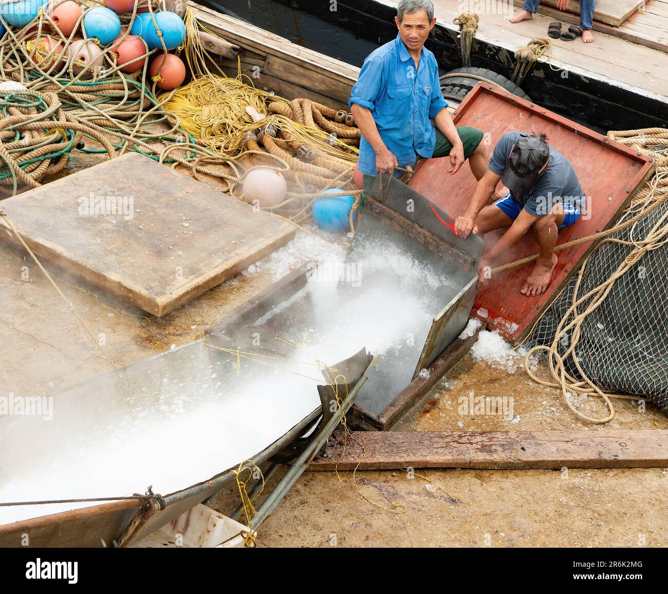 Fischer laden zerstoßenes Eis auf ihr Boot, um den Fang in Thanh Hoa, Vietnam, zu kühlen. Stockfoto