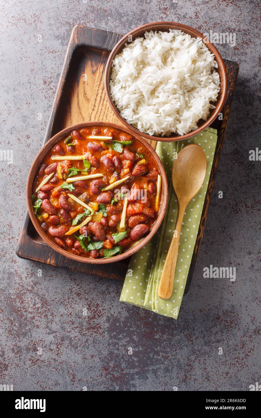 Rajma Masala ist eine köstliche Soße, die durch Kochen von roten Bohnen mit Zwiebeln, Tomaten und einfachen Gewürzen mit Reis aus nächster Nähe auf einem Holztablett auf der Ta hergestellt wird Stockfoto