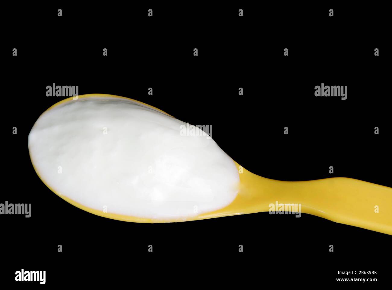 Naturjoghurt auf einem gelben Plastiklöffel Stockfoto