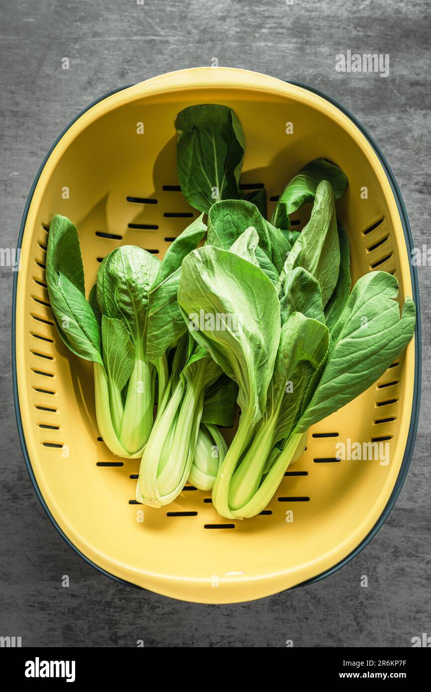 Grünes Gemüse aus Shanghai, das auf einem mit Stein gemusterten Backboard in einem Waschbecken gelagert wird. Stockfoto