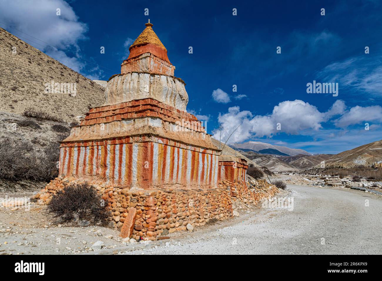 Farbenfroh gemalte buddhistische Stupa vor der Berglandschaft, erodierte Landschaft und Häuser von Garphu dahinter Stockfoto