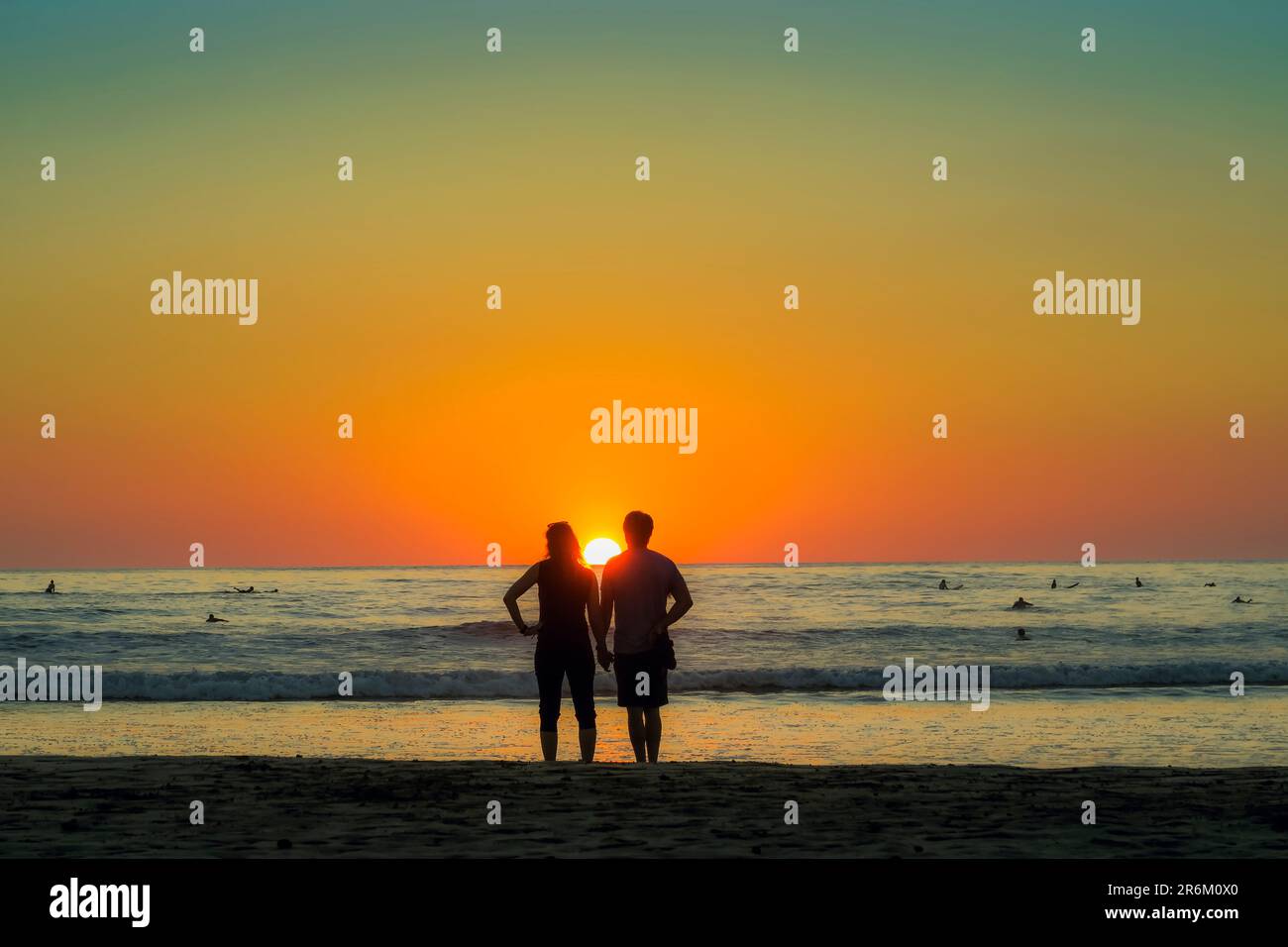 Ein Paar hält sich am Guiones Beach, wo Leute sich zum Surfen versammeln und den Sonnenuntergang beobachten, Playa Guiones, Nosara, Guanacaste, Costa Rica, Mittelamerika Stockfoto