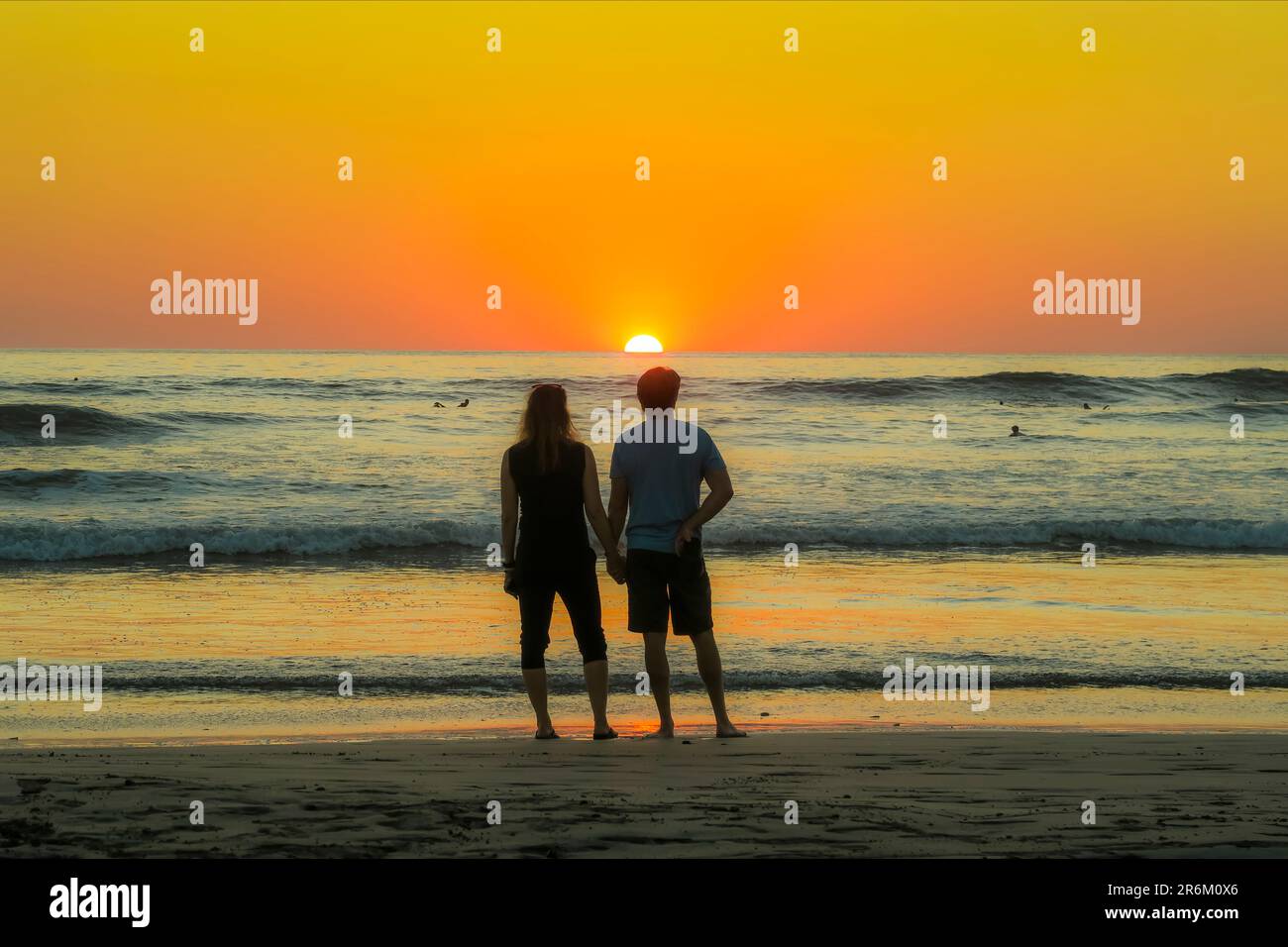 Ein Paar hält sich am Guiones Beach, wo Leute sich zum Surfen versammeln und den Sonnenuntergang beobachten, Playa Guiones, Nosara, Guanacaste, Costa Rica, Mittelamerika Stockfoto