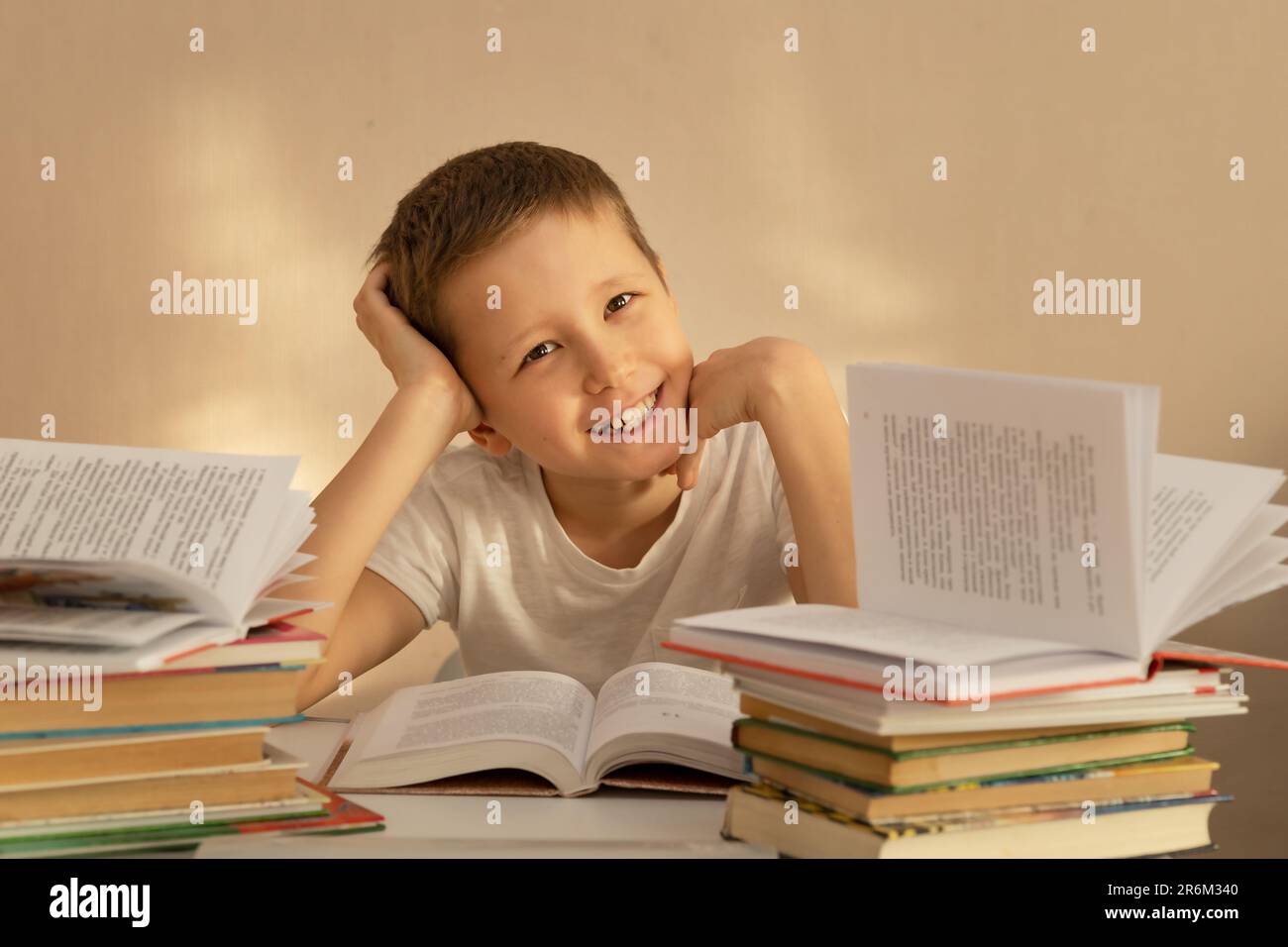 Ein 10-jähriger Junge liest und studiert sorgfältig an einem Tisch mit Büchern Stockfoto