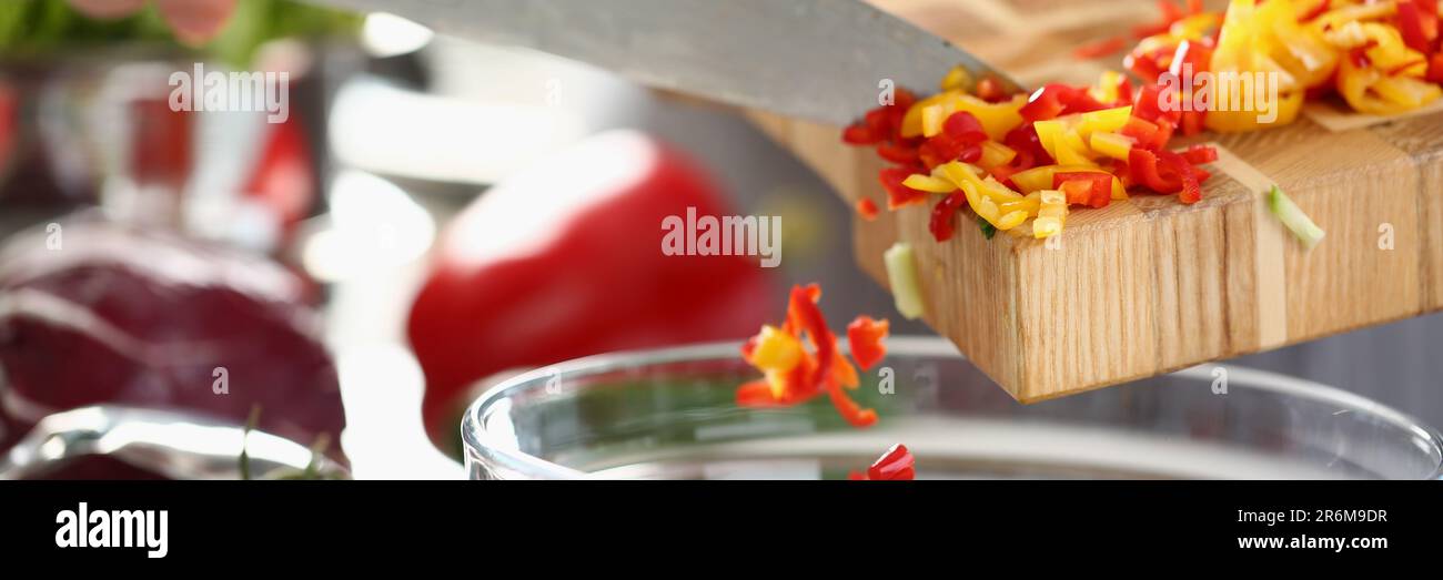 Der Koch gibt gehackten roten gelben Pfeffer zum Salat hinzu Stockfoto