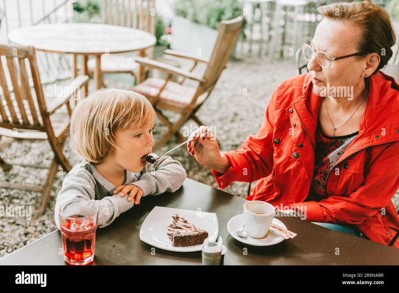 Großmutter und kleiner Junge verbringen Zeit zusammen in einem Café im Freien, essen Schokoladenkuchen, Familienbeziehungen Stockfoto