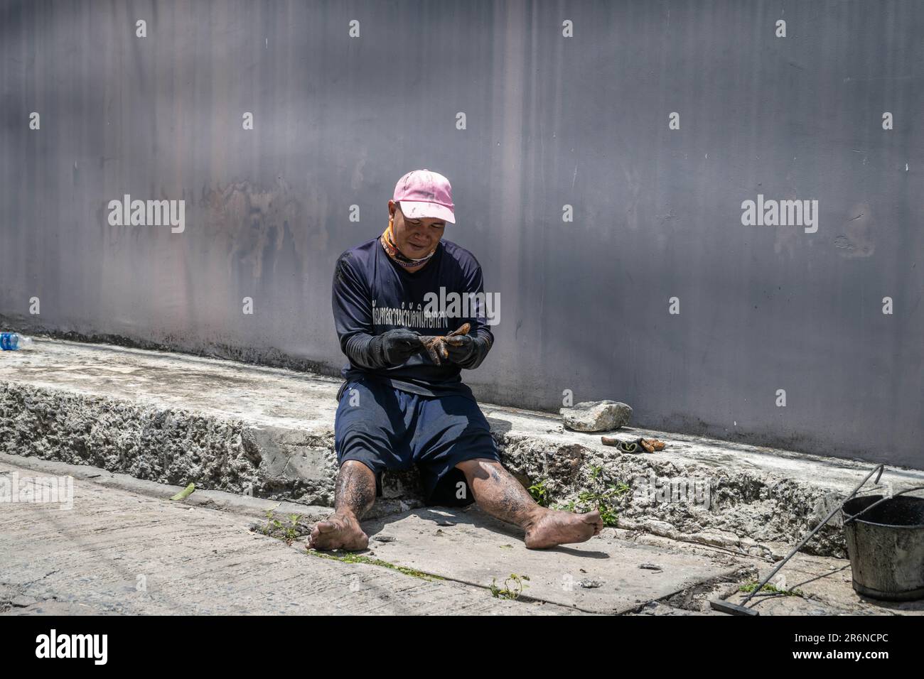 Ein thailändischer Gefangener macht eine Pause, nachdem er die Kanalisation in einer angrenzenden Straße der Lad Prao Road in Bangkok entstaut hat. Die Reduzierung der Strafen durch Arbeit ist eine der Richtlinien der Zusammenarbeit zwischen der Stadtverwaltung von Bangkok und der Strafvollzugsbehörde, die darauf abzielt, die Überbelegung von Gefängnissen im ganzen Land zu verringern, Häftlingen zu ermöglichen, ein Einkommen zu verdienen, bevor sie entlassen werden, und hilft bei den Folgen Der wiederkehrenden Überschwemmungen in der thailändischen Hauptstadt zur Monsunzeit. Stockfoto