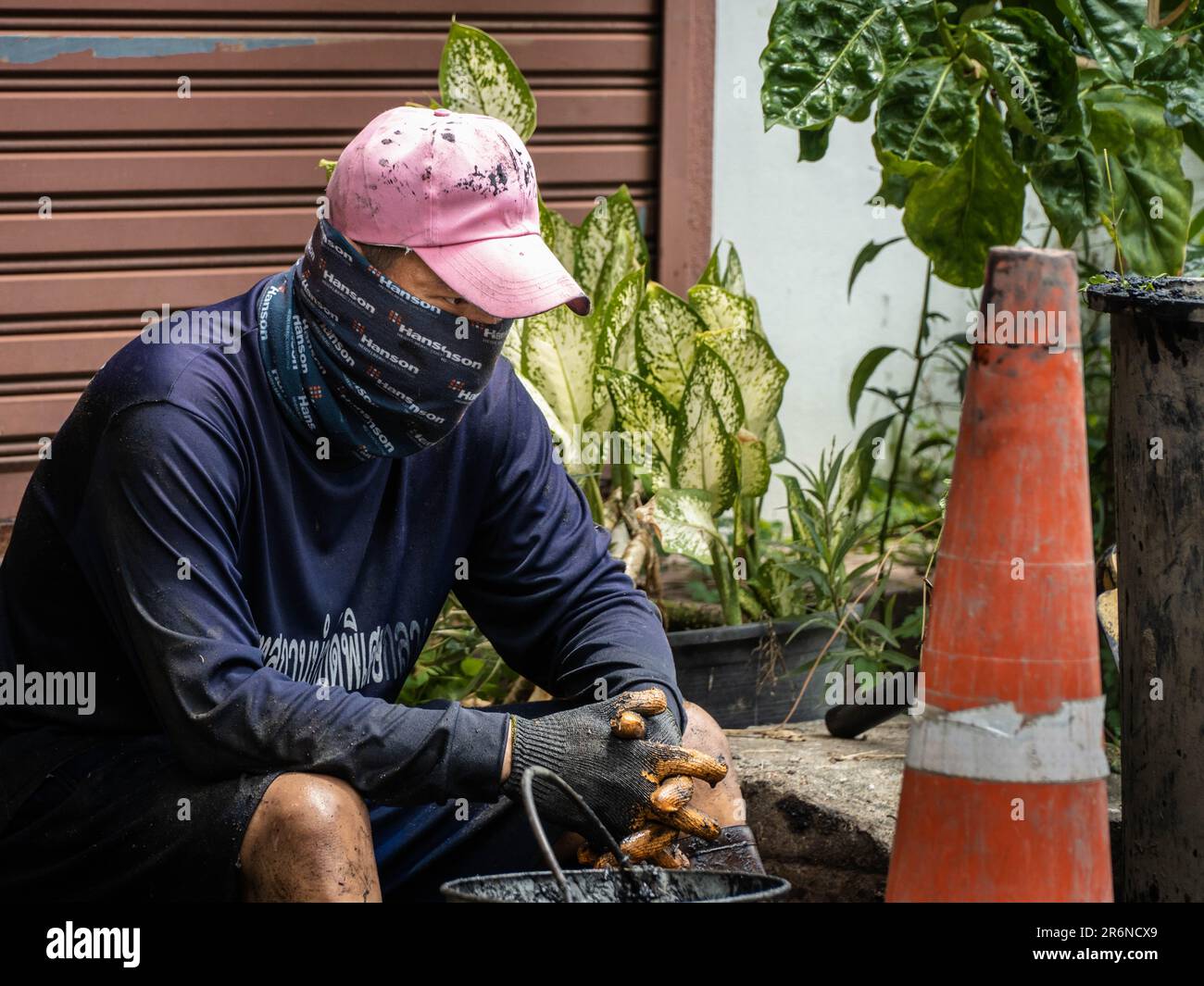 Ein thailändischer Gefangener macht eine Pause, nachdem er die Kanalisation in einer angrenzenden Straße der Lad Prao Road in Bangkok entstaut hat. Die Reduzierung der Strafen durch Arbeit ist eine der Richtlinien der Zusammenarbeit zwischen der Stadtverwaltung von Bangkok und der Strafvollzugsbehörde, die darauf abzielt, die Überbelegung von Gefängnissen im ganzen Land zu verringern, Häftlingen zu ermöglichen, ein Einkommen zu verdienen, bevor sie entlassen werden, und hilft bei den Folgen Der wiederkehrenden Überschwemmungen in der thailändischen Hauptstadt zur Monsunzeit. Stockfoto