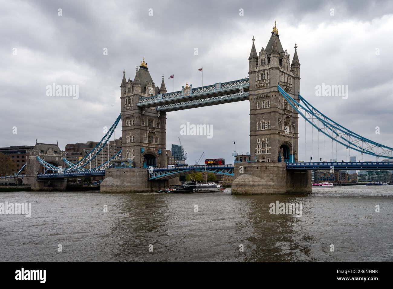 LONDON, ENGLAND - 18. APRIL 2023: Blick auf die Tower Bridge, die Themse und einen roten Londoner Bus an einem im Frühling bewölkten Nachmittag Stockfoto