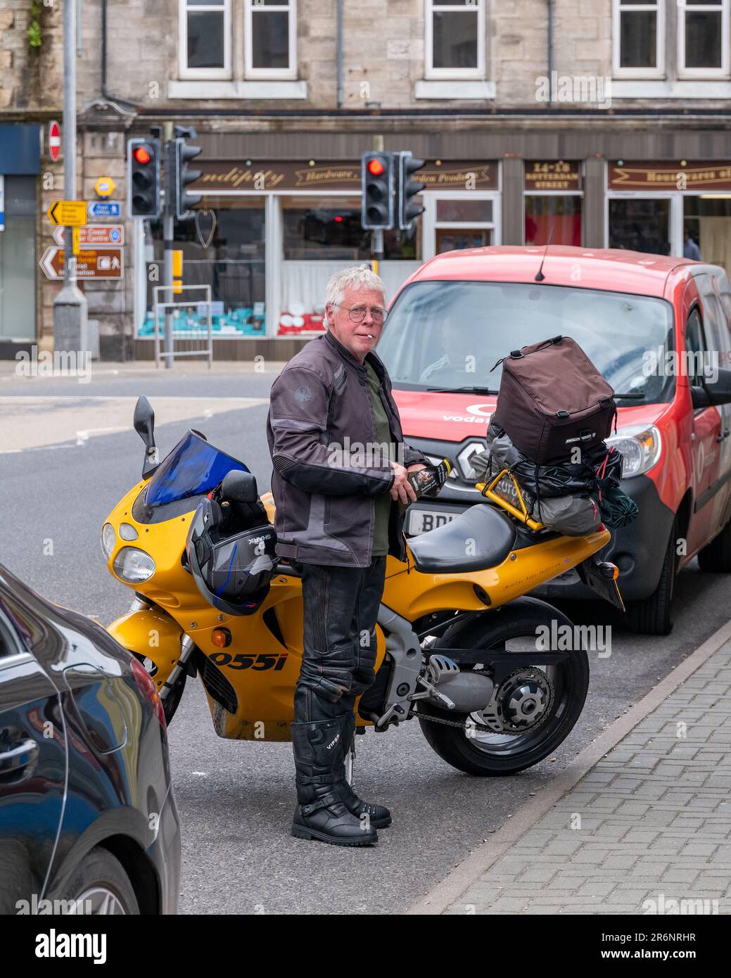 9. Juni 2023 Thurso, Schottland. Das ist ein Biker in Lederausrüstung, der neben seinem Triumph Daytona 955i auf der Straße angehalten hat, kurz davor, eine Zigarette zu drehen. Stockfoto