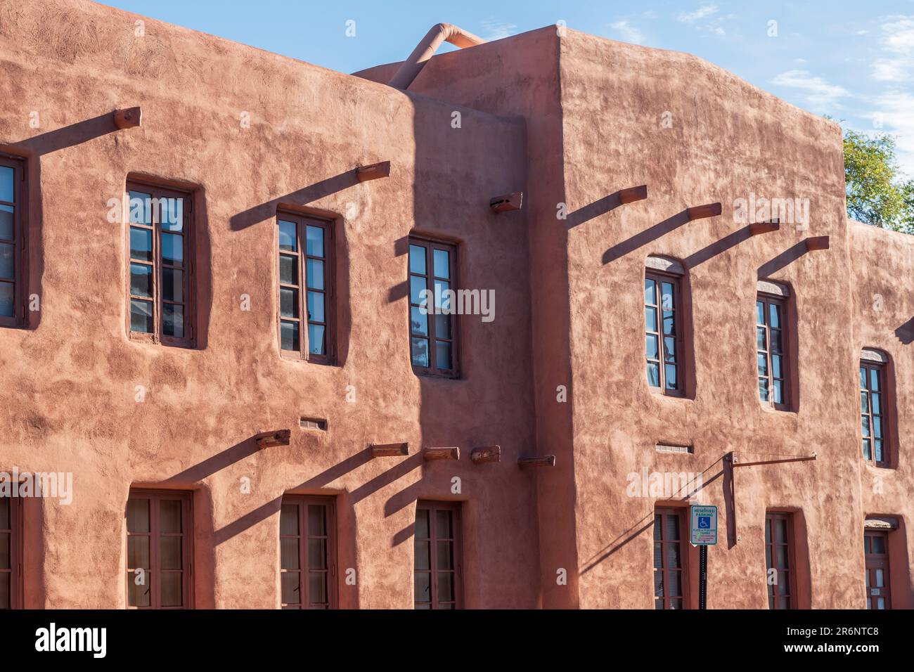 Horizontales Bild des Äußeren des Institue of American Indian Arts im Morgenlicht mit diagonalen Schatten aus den Holzbalken. Stockfoto