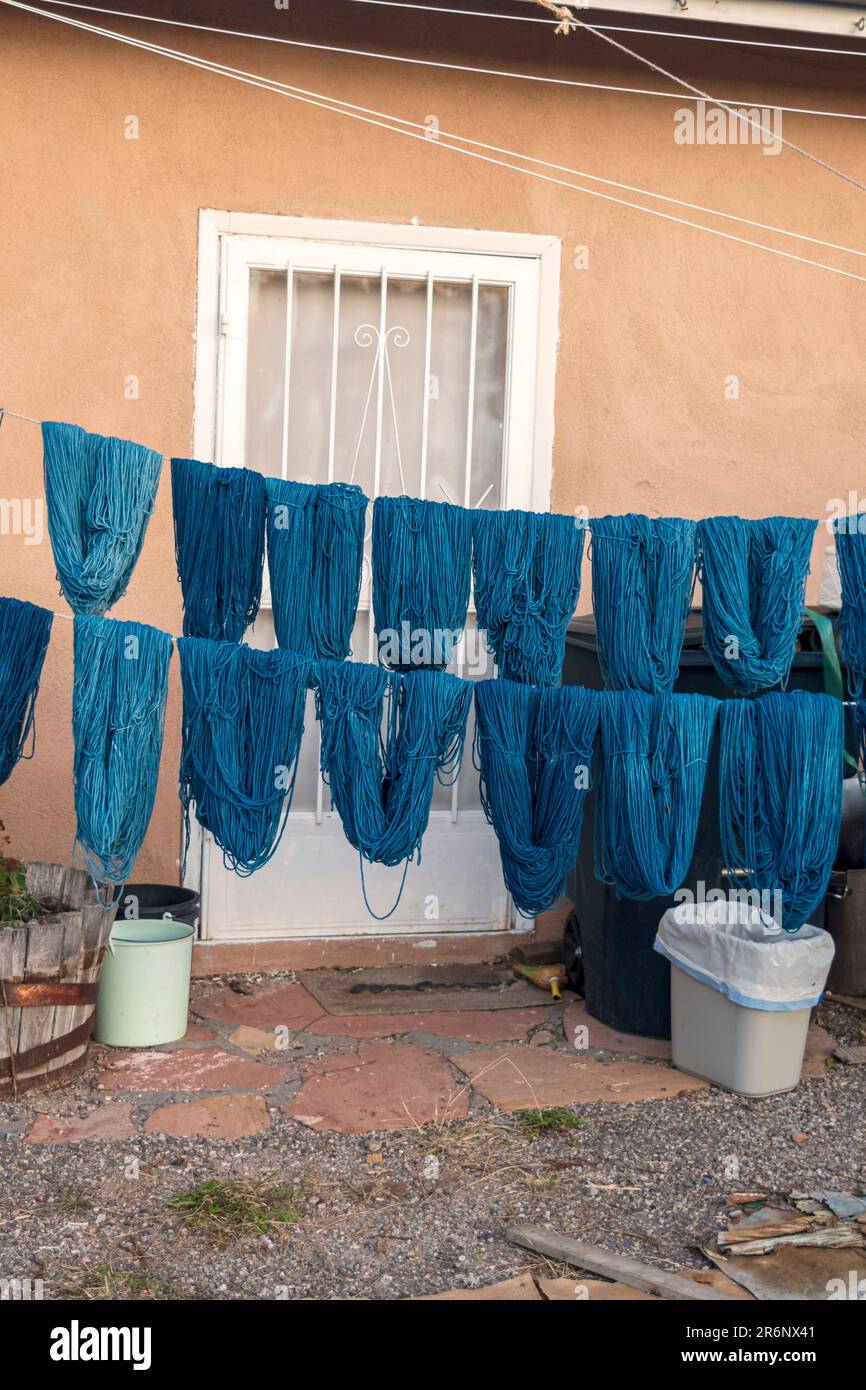 Im Trujillo Weaving Shop in Chimayo, New Mexico, USA, werden im Freien trockene Sträucher aus handgefärbtem Garn in blauen Schattierungen an Seilen angeboten. Stockfoto