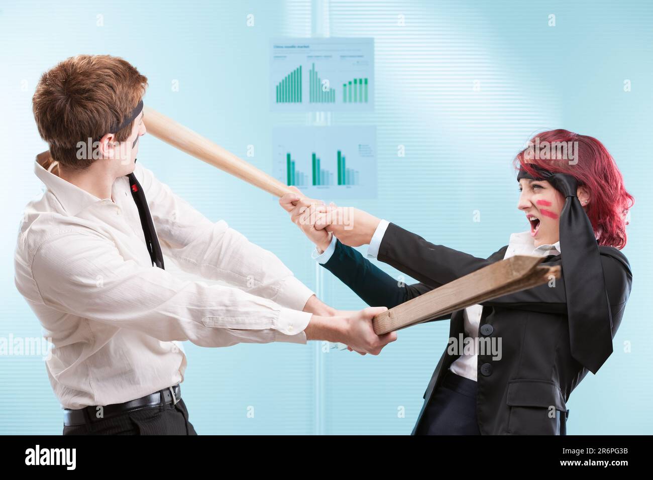 Mitarbeiter, die Büromöbel für einen Scheinkampf benutzen. Business Warriors oder Friendly Fire in Aktion? Stockfoto