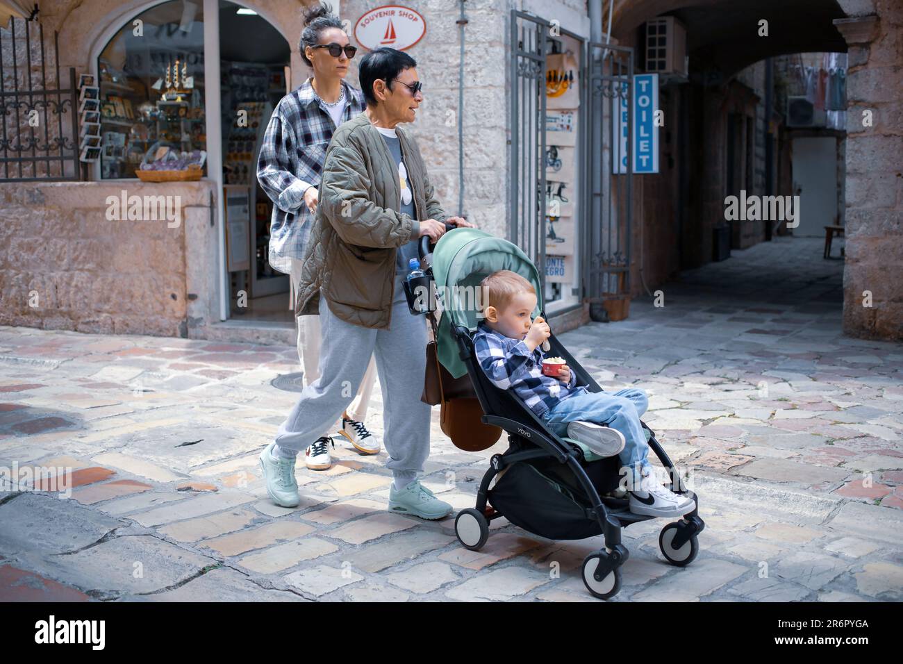 Kotor, Montenegro, 13. April 2023: Ein kleiner Junge im Kinderwagen auf einem Spaziergang mit seiner Mutter und Großmutter Stockfoto