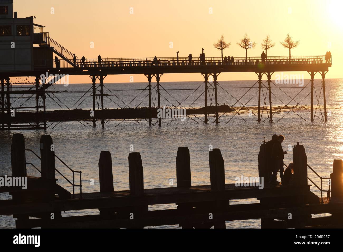 Wunderschöner Sonnenuntergang in der Universität und Touristenstadt Aberystwyth mit dem Pier Biergarten und Fußsteg in Silhouette Stockfoto