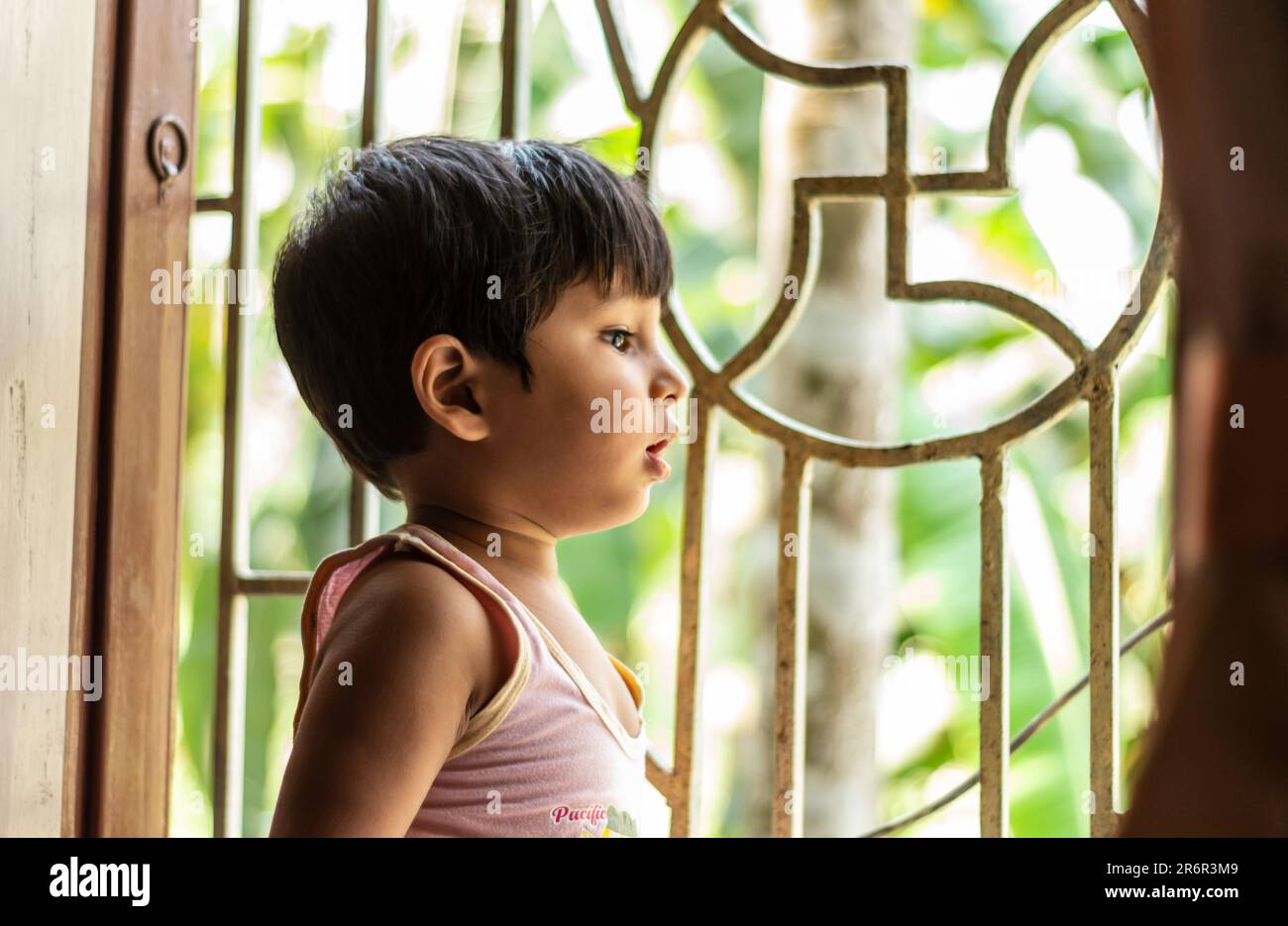 Das Baby schaut aus dem Fenster und wartet auf Mutter, die nach Hause kommt. Asiatischer Indianer, 2 Jahre alt. Stockfoto