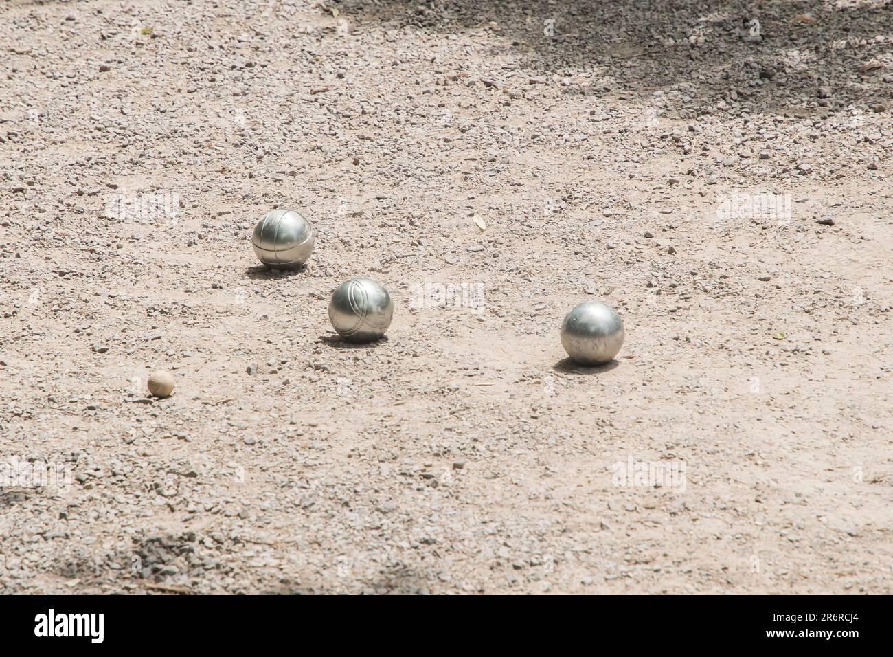 Petanque-Bälle (Boule) in der Nähe des Zielballs auf Schotterparkplatz Stockfoto