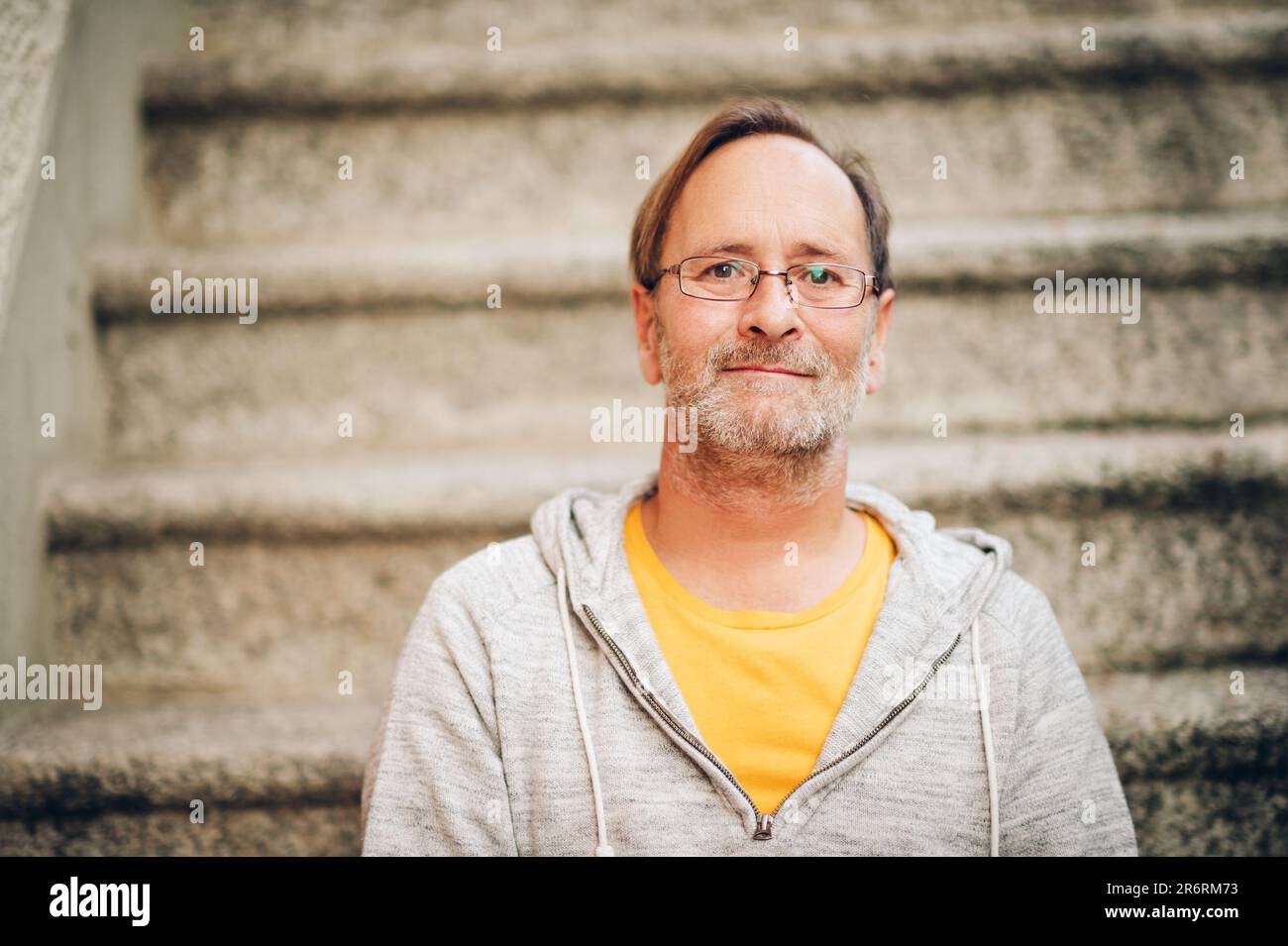 Außenporträt eines 50-jährigen Mannes mit grauer Kapuze und Brille Stockfoto