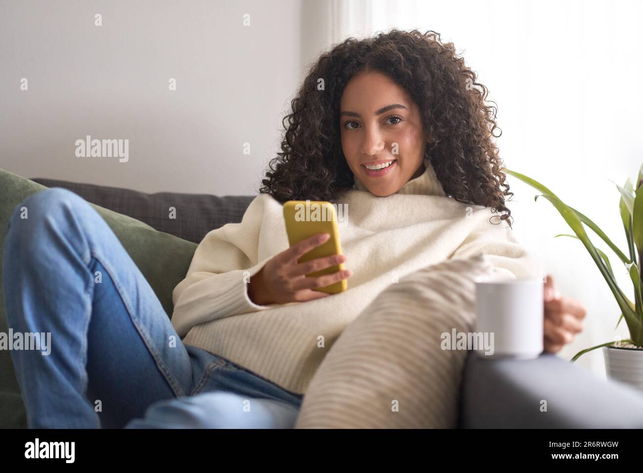 Junge hübsche Frau, die zu Hause mit dem Mobiltelefon telefonieren kann. Stockfoto