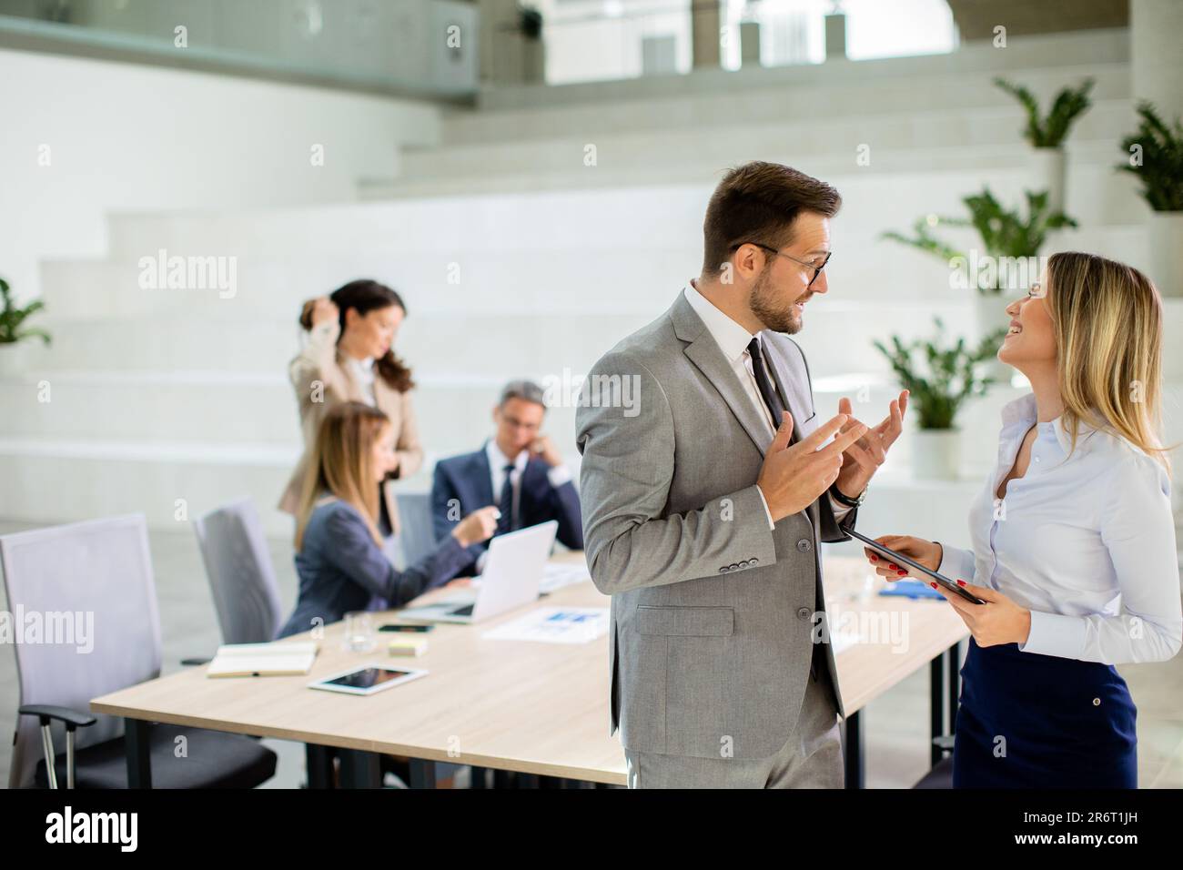 Attraktives junges Geschäftspaar, das sich die finanziellen Ergebnisse auf einem digitalen Tablet vor seinem Team im Büro ansieht Stockfoto