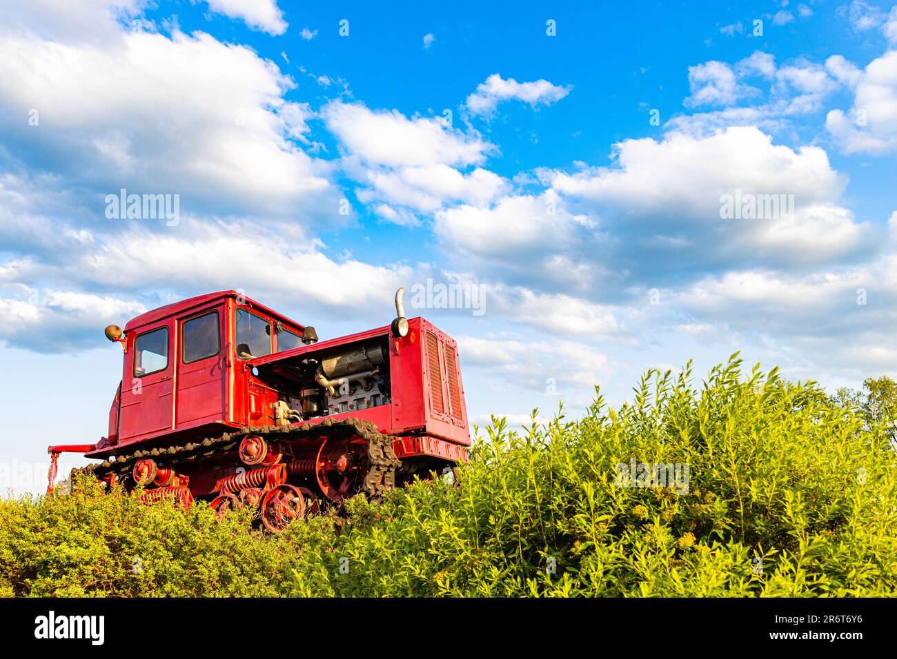 Der rote Traktor des alten Modells steht auf dem Feld. Traktor auf dem Feld. Traktor fährt im Gelände. Der alte sowjetische Traktor steht auf dem Feld. Stockfoto