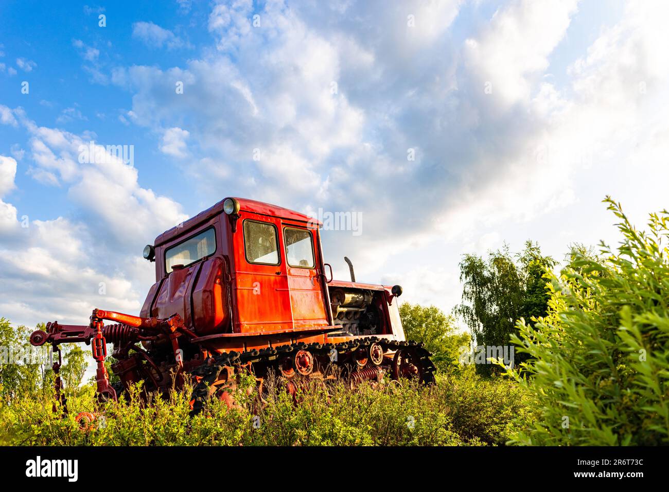 Der rote Traktor des alten Modells steht auf dem Feld. Roter Traktor. Alter Traktor. Traktor auf dem Feld. Crawler Stockfoto